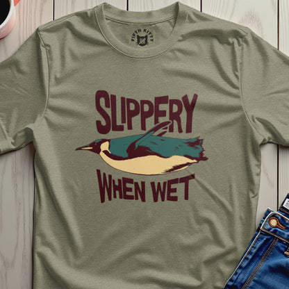Green t-shirt with "Slippery When Wet" text and a falling penguin graphic.