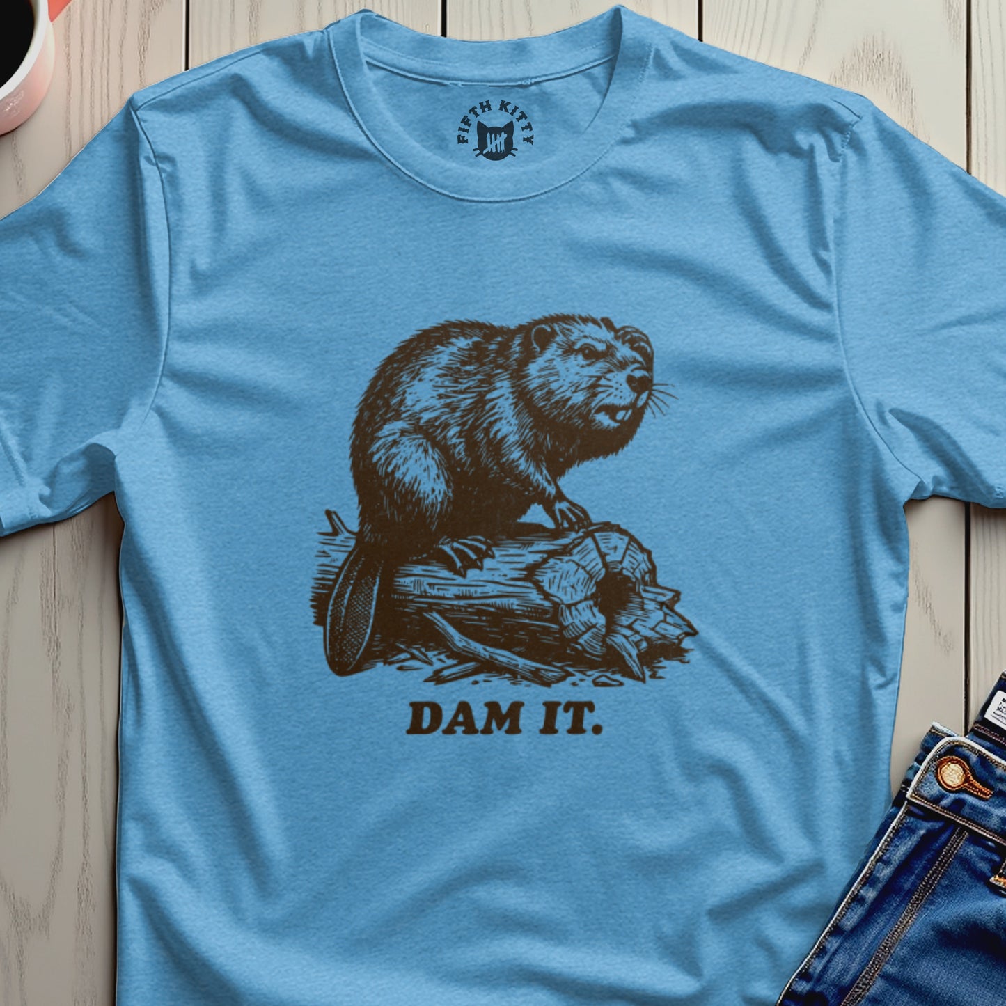 Brown beaver on log with text "DAM IT." on a blue t-shirt.