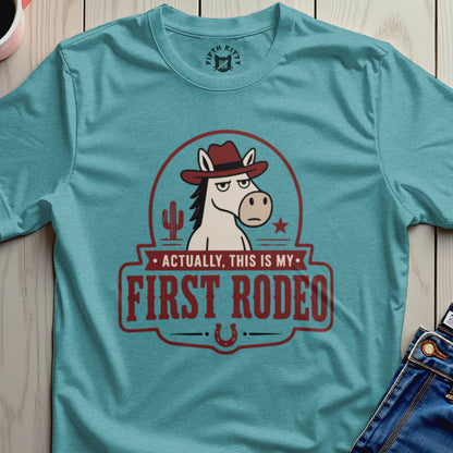 Turquoise t-shirt with a vintage-style graphic of a horse wearing a hat and the text "Actually, This Is My First Rodeo."