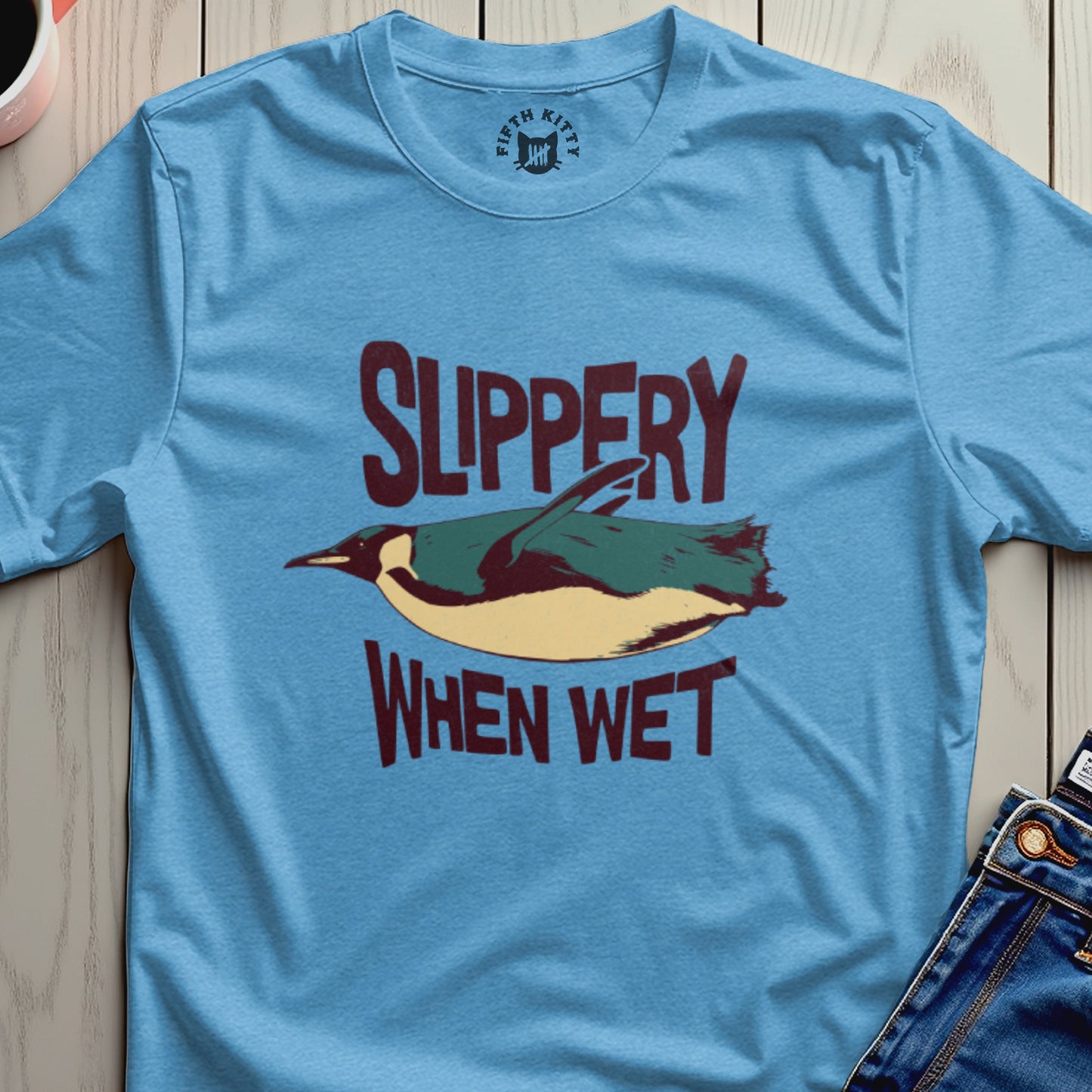 Light blue t-shirt with a penguin graphic and text "SLIPPERY WHEN WET".