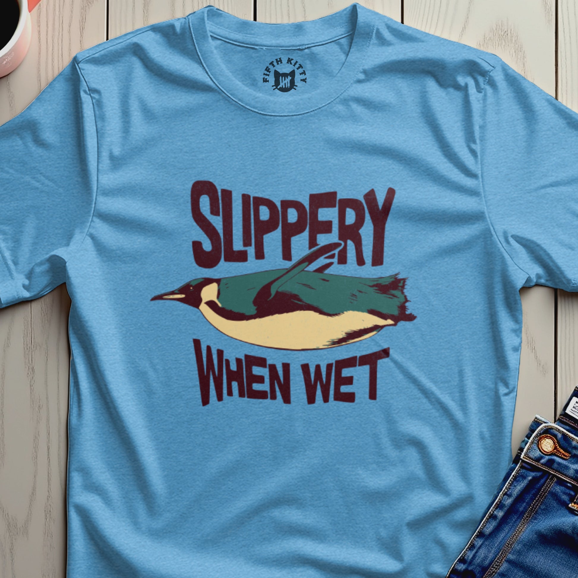 Light blue t-shirt with a penguin graphic and text "SLIPPERY WHEN WET".