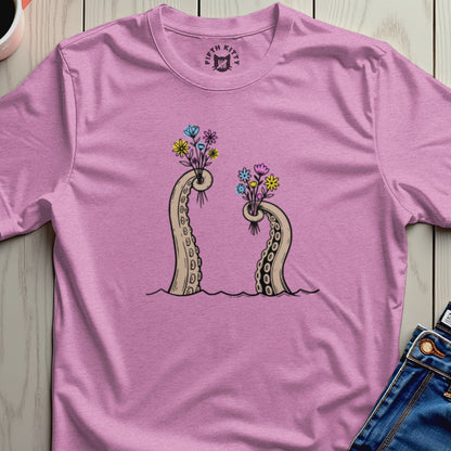 Pink t-shirt with illustration of two octopus tentacles holding bouquets of flowers.