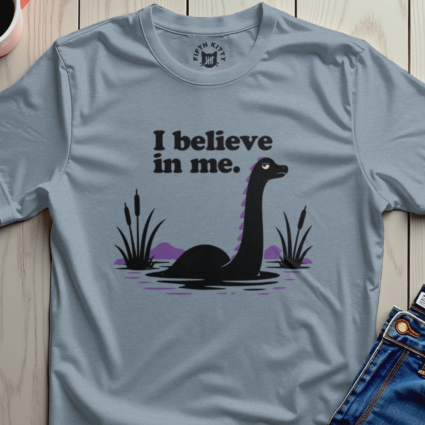 T-shirt graphic with a black loch ness monster and text that says "I believe in me."