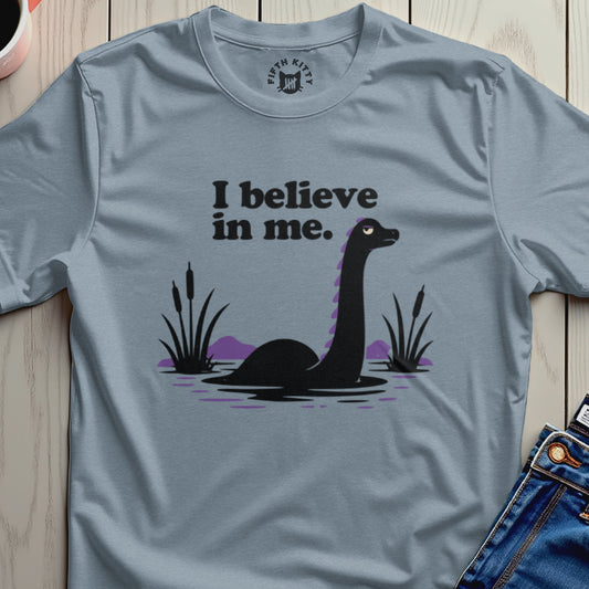 T-shirt graphic with a black loch ness monster and text that says "I believe in me."