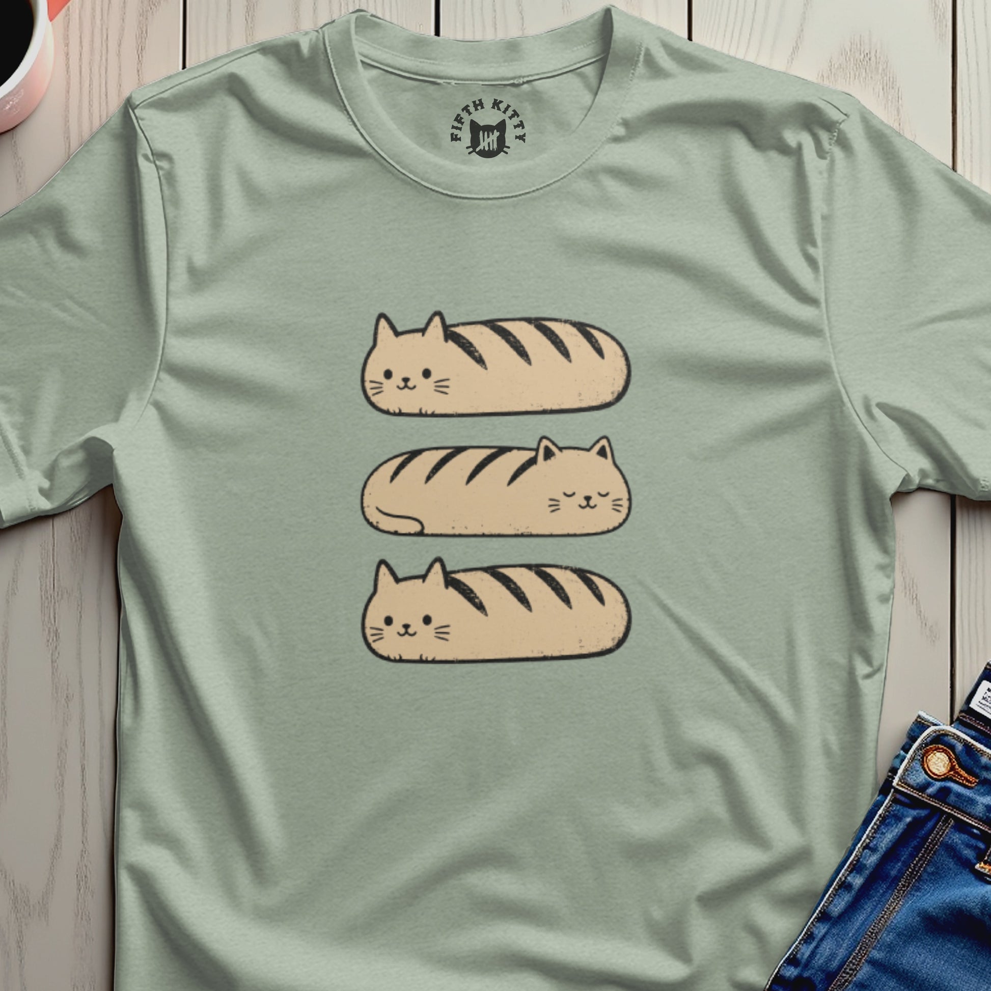 Light green t-shirt with three cartoon cat loaf designs stacked vertically.