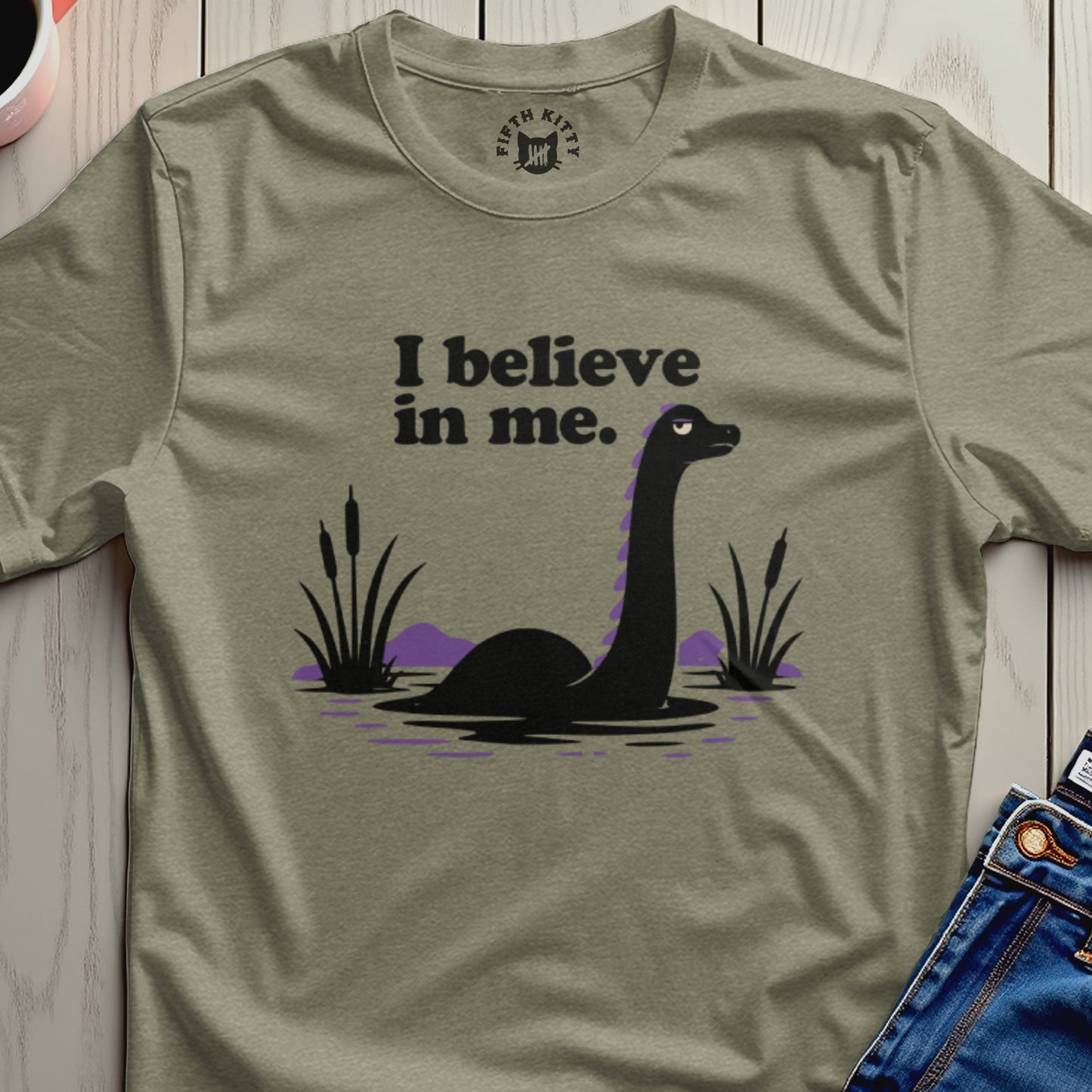 Green t-shirt with Loch Ness Monster graphic and text "I believe in me."