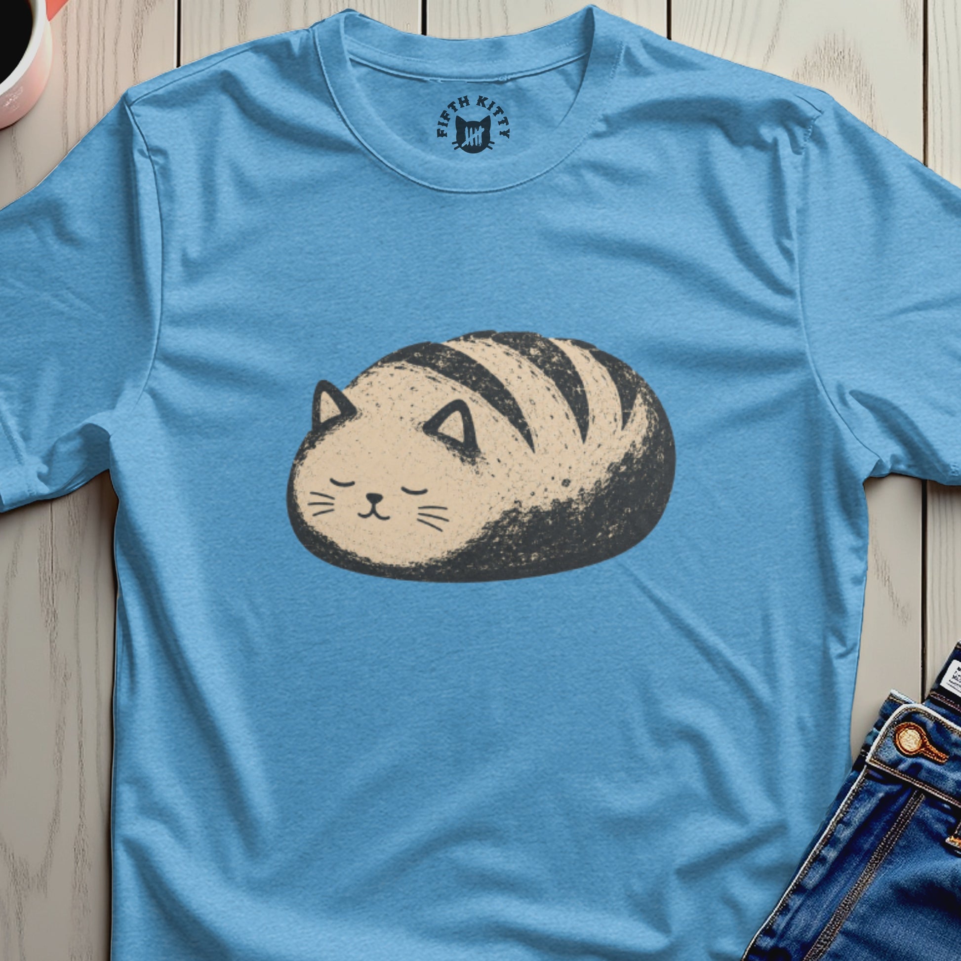 Blue t-shirt with a cartoon drawing of a cat shaped like a loaf of bread.