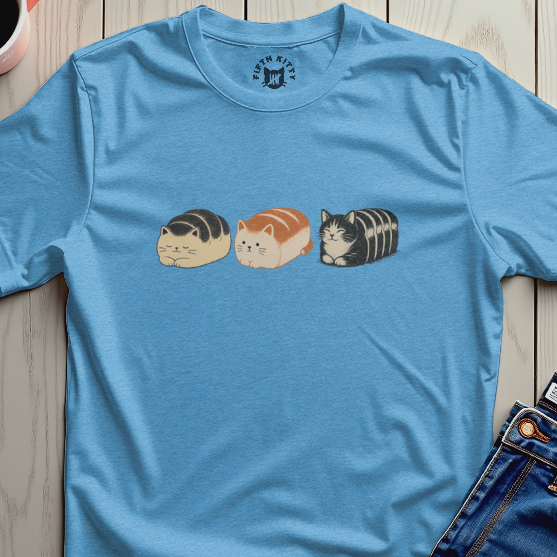 Three loaf-shaped cats in cartoon style on a blue t-shirt with Fifth Kitty logo.