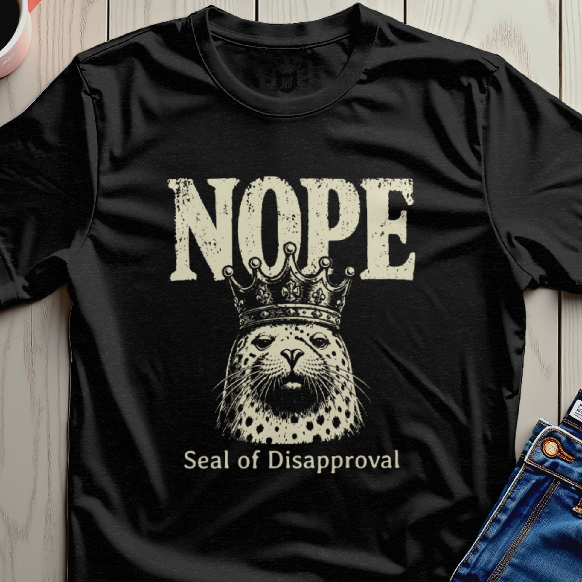 Black t-shirt with "NOPE Seal of Disapproval" text and crowned seal graphic.