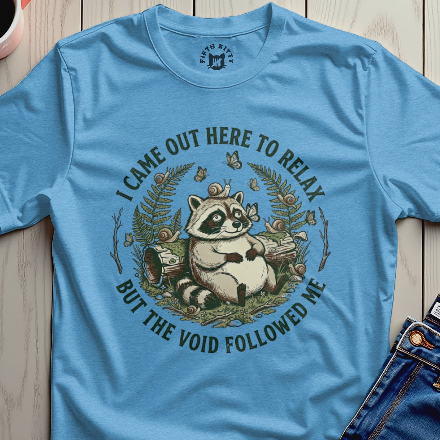 T-shirt with raccoon graphic and text "I came out here to relax but the void followed me".