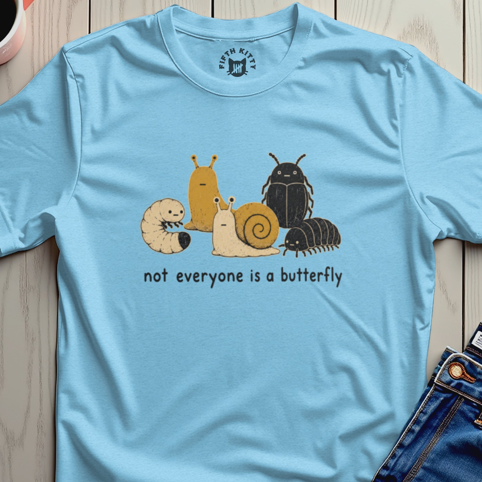 Light blue t-shirt with cartoon bugs and the text "not everyone is a butterfly".