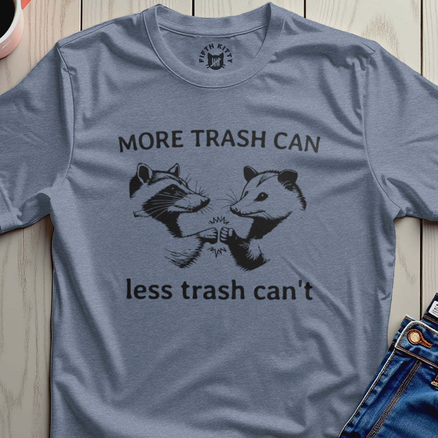 Blue t-shirt with trash panda and opossum fists bumping, saying "More trash can, less trash can't".