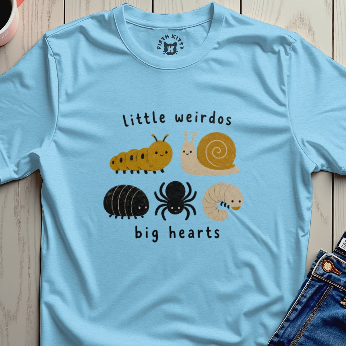 Light blue t-shirt with cartoon caterpillar, snail, woodlouse, spider, and grub with text "little weirdos big hearts".