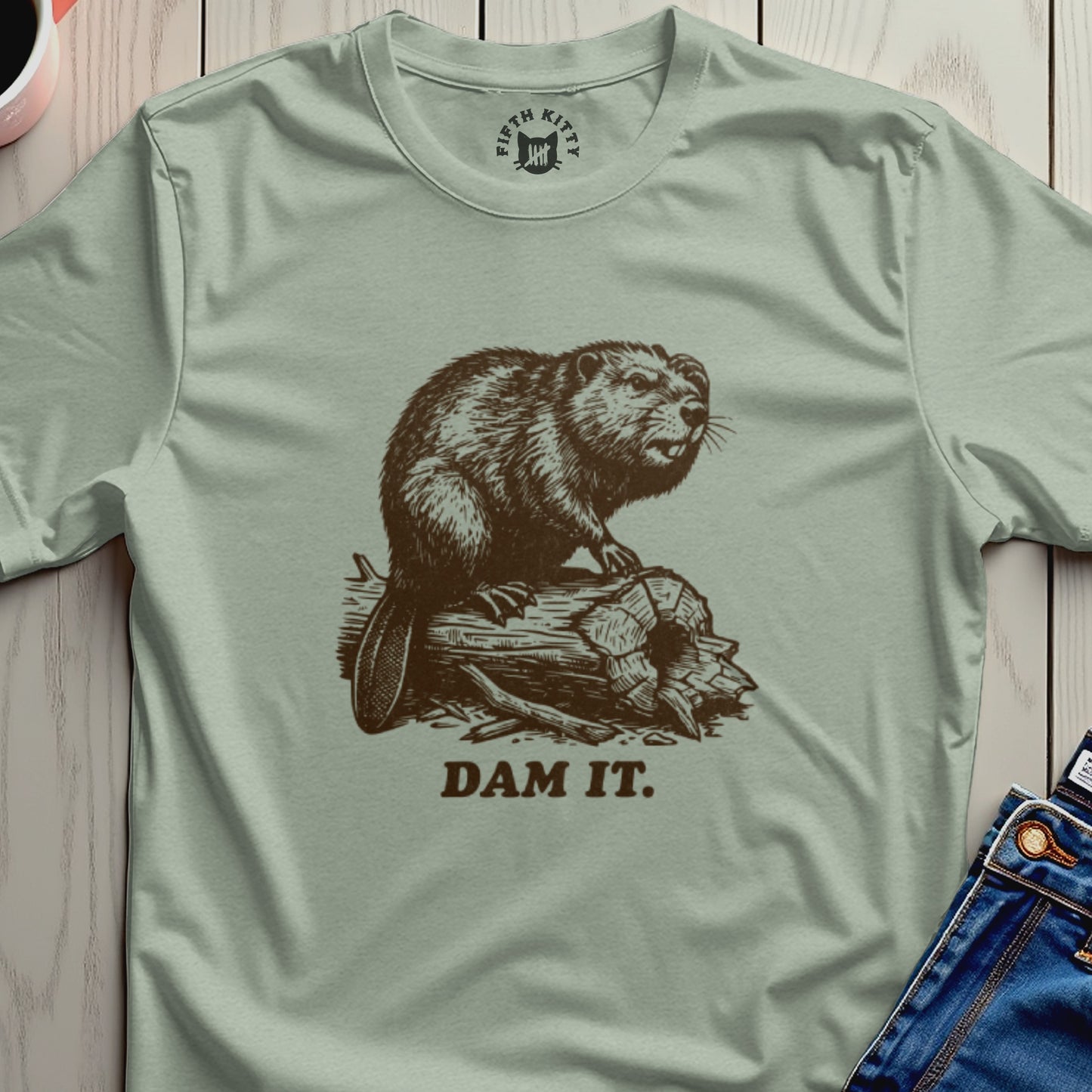 Brown beaver on a log with "DAM IT." text on a light green t-shirt.