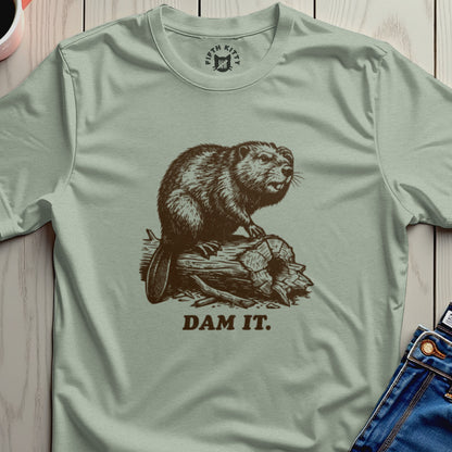 Brown beaver on a log with "DAM IT." text on a light green t-shirt.