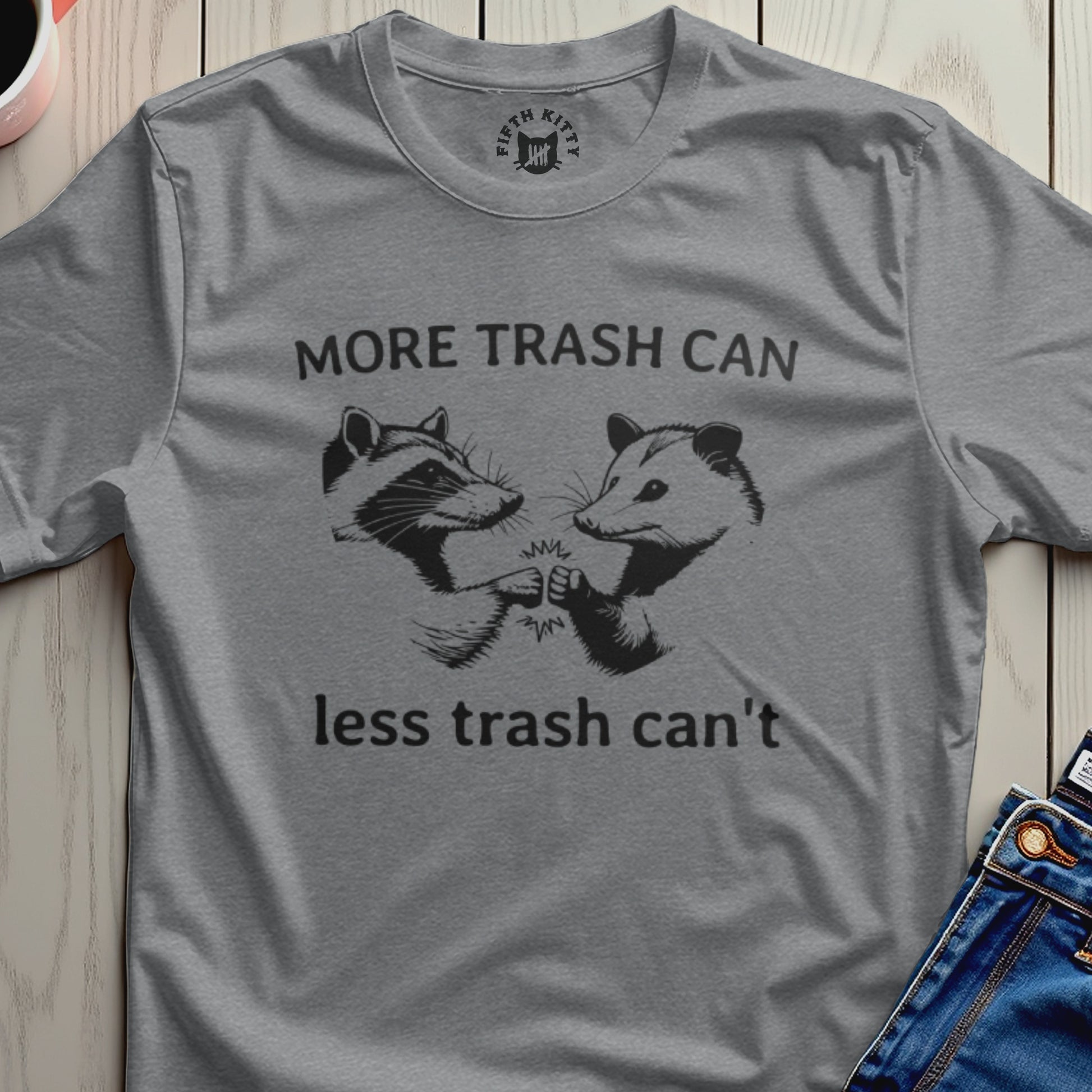 Grey t-shirt with graphic of raccoon and possum fist-bumping, saying "More trash can, less trash can't".